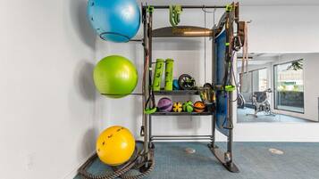 Ein Heimfitnessraum mit Trainingsgeräten, darunter eine Klimmzugstange, Medizinbälle und ein Ergometer.
