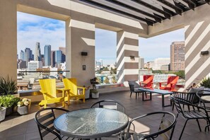 A rooftop terrace with outdoor seating, a city view, and a modern architectural design.