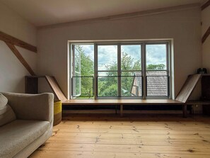 Ein Zimmer mit großem Fenster, Holzboden und einer Couch.