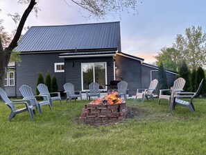 A house with a fire pit and Adirondack chairs in the yard. - 2 king beds w/private baths •firepit •walk to town and Lake Charlevoix (Boyne City)