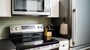 A kitchen with a stainless steel stove, microwave, and refrigerator. - 2 king beds w/private baths •firepit •walk to town and Lake Charlevoix (Boyne City)