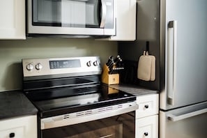 A kitchen with a stainless steel stove, microwave, and refrigerator. - 2 king beds w/private baths •firepit •walk to town and Lake Charlevoix (Boyne City)