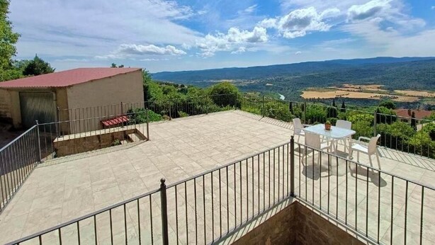 A terrace with a table and chairs, a small building with a red roof, and a scenic view of the landscape. - Apartment in the village of Riglos, at the foot of the Mallos de Riglos (Riglos)