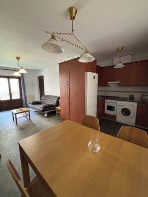 A compact living space with a dining area, kitchenette, and a sofa.