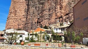 A building with a stone facade, a clear blue sky, and a mountainous backdrop. - Apartment in the village of Riglos, at the foot of the Mallos de Riglos (Riglos)
