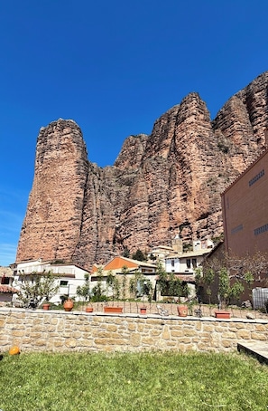 A building with a stone facade, a clear blue sky, and a mountainous backdrop.