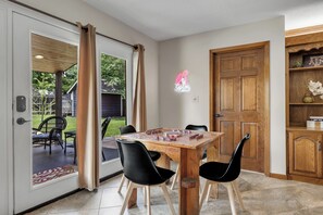 Ein Essbereich mit einem Holztisch, schwarzen Stühlen und Blick auf den Garten durch eine Glastür.