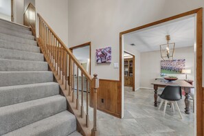Eine Treppe mit Holzbalkonen, ein Essbereich mit Tisch und Stühlen sowie eine Küche mit Schränken.