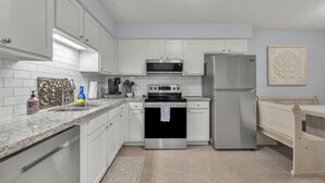 Una cocina moderna con armarios blancos, electrodomésticos de acero inoxidable y un banco de madera.