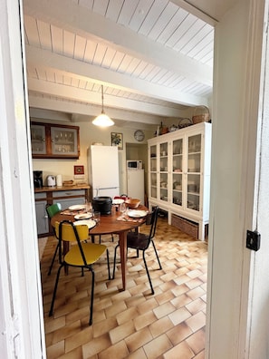 Ein Essbereich mit Holztisch, Stühlen, einer Hängeleuchte und einer Küche im Hintergrund.