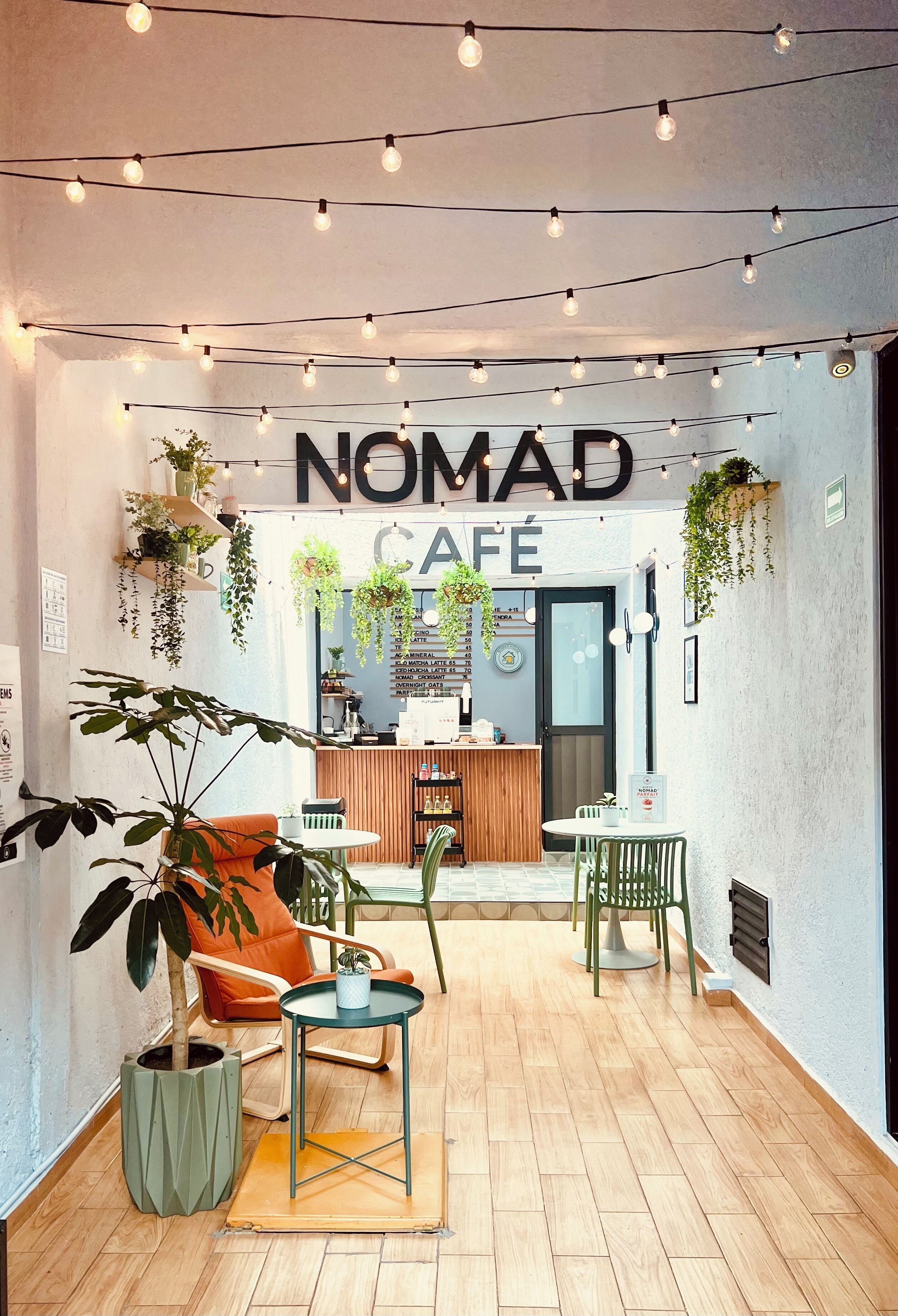 A cozy cafe interior with a wooden floor, a bar area, and hanging plants.