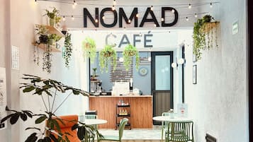 A cozy cafe interior with a wooden floor, a bar area, and hanging plants.