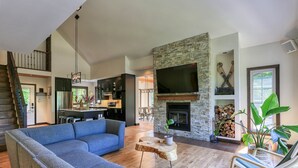 Een moderne woonkamer met een stenen openhaard, een grote televisie en een blauwe modulaire bank.