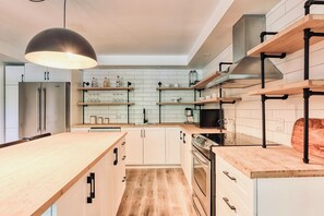 A modern kitchen with a central island, built-in appliances, and open shelving. - A rustic cabin near a lake, 45 minutes from Quebec City—perfect for families! (Saint-Raymond)