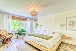 A bedroom with a bed, a chair, a plant, and a wall-mounted artwork. - A rustic cabin near a lake, 45 minutes from Quebec City—perfect for families! (Saint-Raymond)