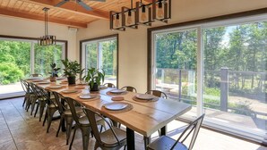 Een eetgedeelte met een lange tafel, stoelen en potplanten.