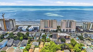 A coastal hotel with multiple buildings, a parking lot, and a view of the ocean. - Coco Cottage w Outdoor Bar and TV Walk to Beach (North Myrtle Beach)
