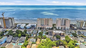 A coastal hotel with multiple buildings, a parking lot, and a view of the ocean. - Coco Cottage w Outdoor Bar and TV Walk to Beach (North Myrtle Beach)