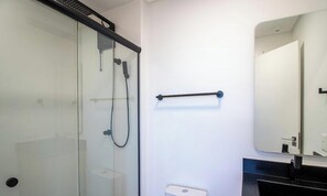 Um banheiro moderno com box de vidro, porta-toalhas e vaso sanitário.
