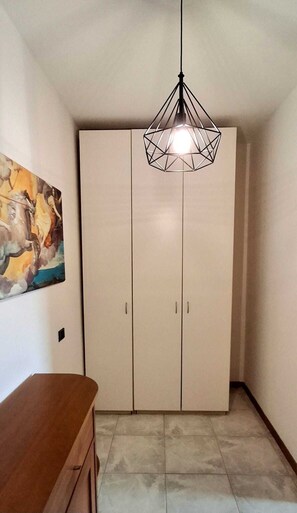 A room with a wardrobe, a painting, and a hanging light fixture. - Bergamo Central Flat in the heart of the city (Bergamo)