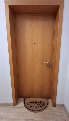 Eine Holztür mit Fußmatte, auf der 'WELCOME' steht.