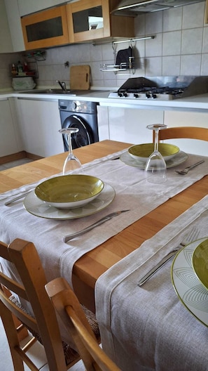 Une cuisine équipée d’une table à manger pour deux personnes, d’un lave-linge et d’une cuisinière.