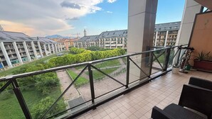 Uma varanda com vista para uma área residencial, móveis de exterior e um vaso de planta.