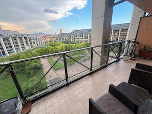 Ein Balkon mit Blick auf ein Wohngebiet, Gartenmöbel und einem Blumentopf.