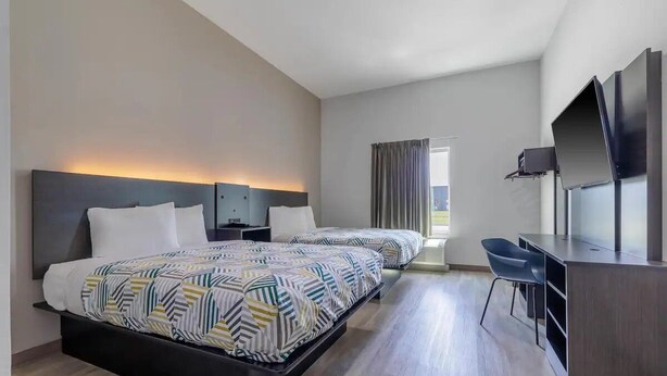 Ein Hotelzimmer mit zwei Betten, einem Schreibtisch, einem Stuhl und einem Fernseher.