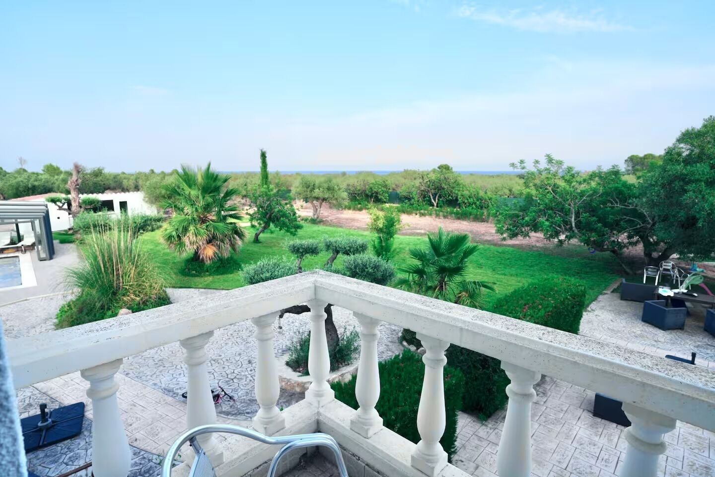 A balcony with a view of a well-maintained garden and a distant landscape.