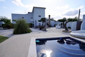 A swimming pool with a tiled deck, a white building with a flat roof, and a gravel path. - Large Family Villa in L'Ametlla de Mar – Spacious Garden, Bar, and Pool (L'Ametlla de Mar)