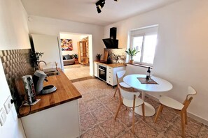 A modern kitchen with a dining area, a built-in oven, and a window with a view. - Large Family Villa in L'Ametlla de Mar – Spacious Garden, Bar, and Pool (L'Ametlla de Mar)