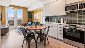 A modern kitchen with a dining area, a large window, and a city view.