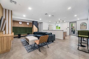 Un intérieur moderne comprenant un canapé, un fauteuil, une petite table, un comptoir d’accueil et une porte.