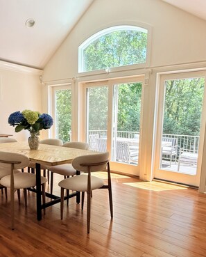 A dining area with a round table, six chairs, and a vase with flowers.