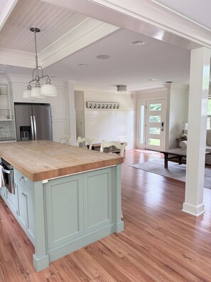 A kitchen with a large island, a refrigerator, and a dining area with chairs.