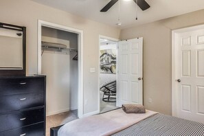 Ein Schlafzimmer mit einem Bett, einem Schminktisch, einem Kleiderschrank und einer Tür zu einem anderen Raum.
