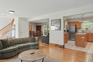 A modern living room with a sectional sofa, a round coffee table, and a dining area with wooden chairs. - Minutes to Kalahari - 4 Bedrooms - Game Room (Pocono Summit)