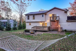 Ein zweistöckiges Haus mit Terrasse, Sitzgelegenheit im Freien und einer Hängematte.