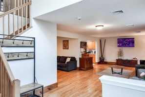 Ein großzügiges Wohnzimmer mit Treppe, Holzboden, Flachbildfernseher und Essbereich.