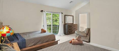 A bedroom with two beds, a dresser, a chair, a lamp, and a ceiling fan.