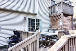 Eine Terrasse mit Grill, Tisch und Stühlen, umgeben von einem Holzzaun.