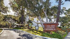 A sign for Ocean Forest Condominiums with a curved road and trees. - Magical Monterey Carmel Pebble Beach travel, family and pet friendly whole Condo (Monterey)