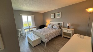 A bedroom with a bed, bedside tables, a desk, and a chair. - Magical Monterey Carmel Pebble Beach travel, family and pet friendly whole Condo (Monterey)