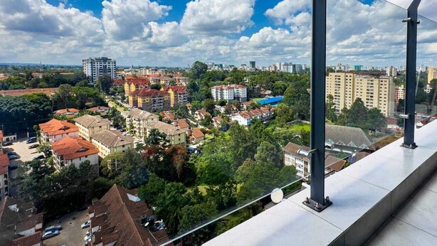 Un edificio alto con vistas a un paisaje urbano, que incluye varios edificios y zonas verdes.