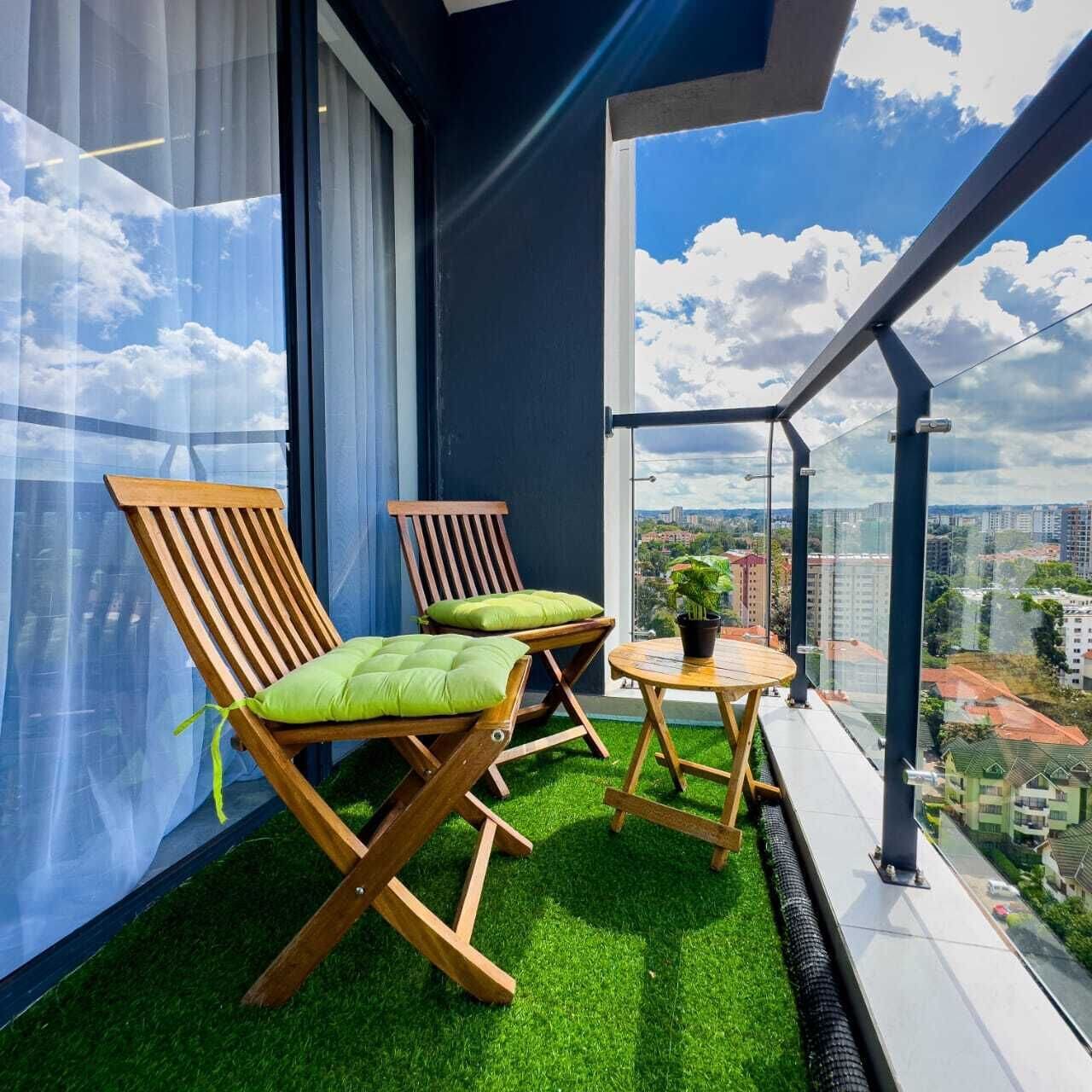 A balcony with two wooden chairs, a small table, and a potted plant.