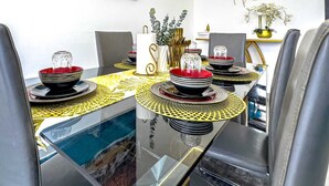 Un comedor con una mesa de vidrio, sillas y un cuadro de una cascada.
