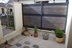 A garden with a wooden fence, steps leading to a door, and various potted plants.