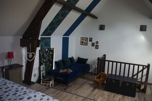 A bedroom with a bed, a dresser, a chair, a chest of drawers, a red lamp, and a heart-shaped decoration.