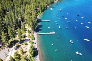 An aerial view of a coastal area with a pier, boats, and dense forest. - Tahoe City Chalet | Sleeps 10 | Summer Beach Club, Hot Tub & Sauna (Tahoe City)